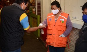 Una mujer aplica desinfectante de manos a un cliente a la entrada de un mercado municipal en la ciudad guatemalteca de San Marcos.