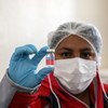 A nurse in Boliva holds up a dose of flu vaccination.
