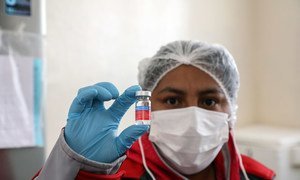 A nurse in Boliva holds up a dose of flu vaccination.