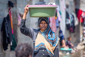 سيدة تحمل حوضا صغيرا لغسل الملابس في مخيم للنازحين في الظهير باليمن.