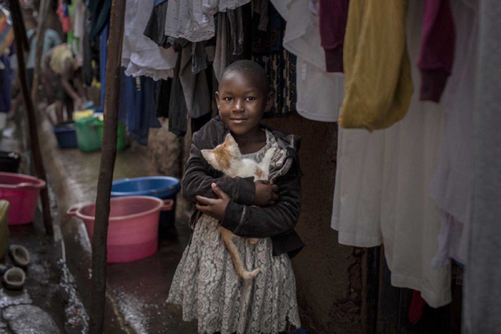 Jennifer Atieno mwenye umri wa miaka 7 akiwa amekumbatia paka wake karibu na makazi duni ya Kibera jijini Nairobi, Kenya.