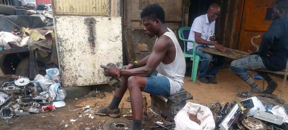 Joven trabajador de los vertederos de desechos electrónico en Ghana desensambla un aparato para obtener los materiales vaiosos.