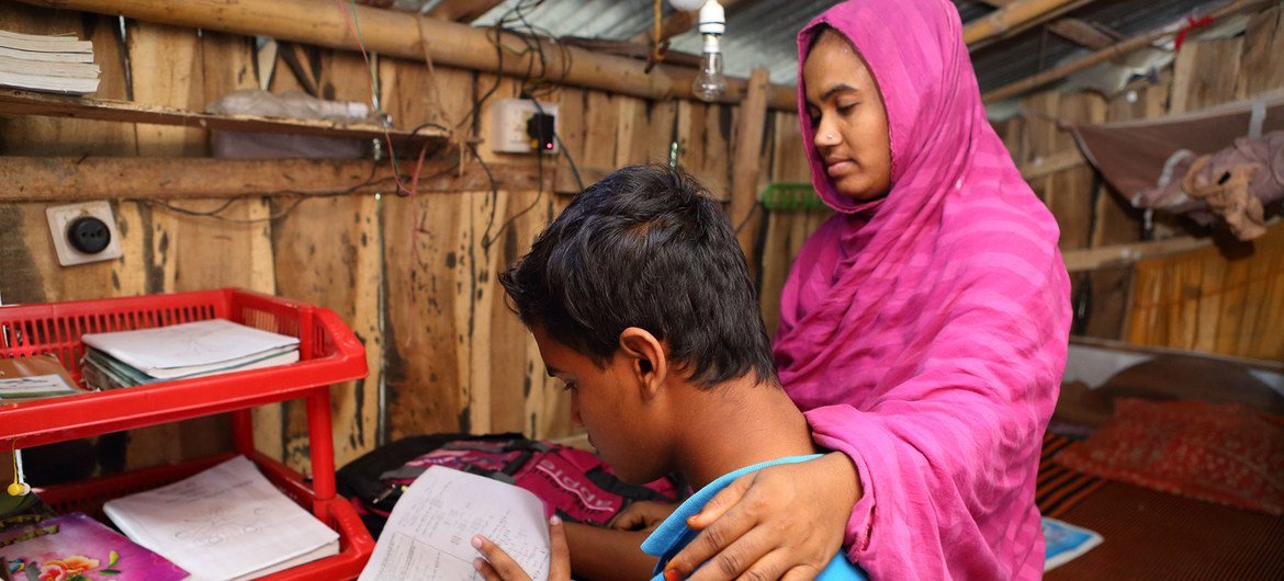 A boy studies at home while his mother sits by his side in Jessore, Bangladesh..