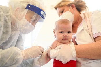 Un bebé recibe una vacuna en Kosovo durante la pandemia de COVID-19.
