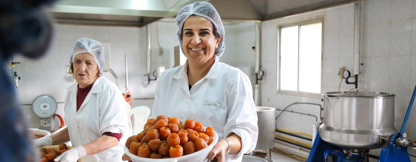 Samira Zoughaib Akiki, Chair of Al Atayeb Cooperative, holding a basket of fresh apple marmalade. 