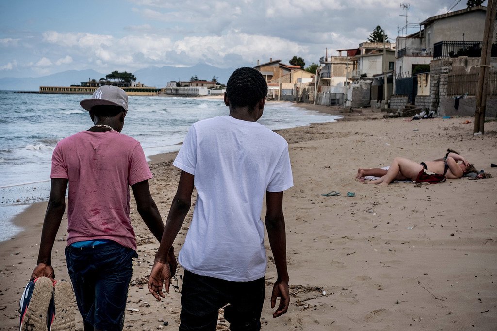 来自冈比亚的两个十几岁的兄弟在意大利的海滩上漫步。2016年，他俩在没有父母陪同的情况穿越了地中海。