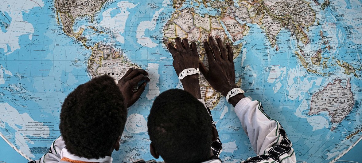 Dois jovens imigrantes gambianos analisam o mapa do mundo depois de atravessar para a Itália, em 2016, desacompanhados dos pais.