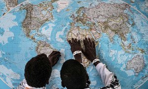 Two young  unaccompanied Gambian migrants look at a map after crossing to Italy. (file) 