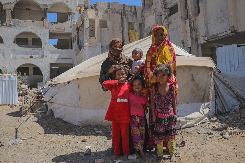 一家也门人站在一个流离失所者营地的帐篷外。