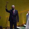 Volkan Bozkir, Président de la 75ème session de l'Assemblée générale, lève le marteau alors que son prédécesseur Tijjani Muhammad-Bande et le Secrétaire général de l'ONU, António Guterres, applaudissent.