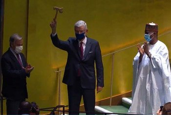 Volkan Bozkir, Président de la 75ème session de l'Assemblée générale, lève le marteau alors que son prédécesseur Tijjani Muhammad-Bande et le Secrétaire général de l'ONU, António Guterres, applaudissent.