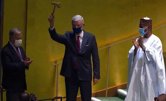 Volkan Bozkir, President of the 75th session of the General Assembly, raises the gavel as Secretary-General António Guterres and outgoing President Tijjani Muhammad-Bande applaud.