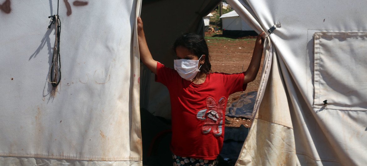 在叙利亚北部的一个营地中，一名年轻女孩戴着口罩，以免感染新冠病毒。
