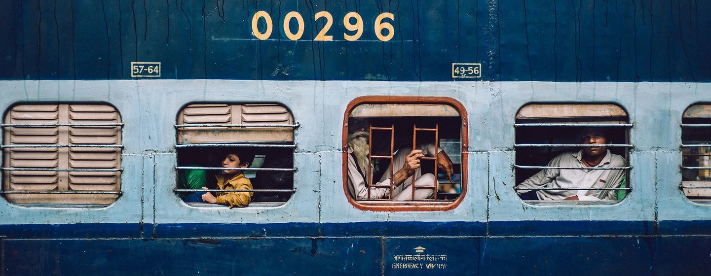 Passengers look out of the window as a train pulls into a railway station in Delhi, India.