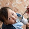 Ulaanbaatar, Mongolia - September 07, 2018: Mother giving porridge mixed with micronutrient powders (MNP) to her one-year old son in their house, in Ulaanbaatar, Mongolia. MNP aim to improve the quality of diets of nutritionally vulnerable groups, such as young children, improving complementary feeding.
