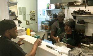 Trainee chef Roberta Mbiua (2nd right) receives his instructions from culinary director Alexander Harris at Emma’s Torch Restaurant, Brooklyn.