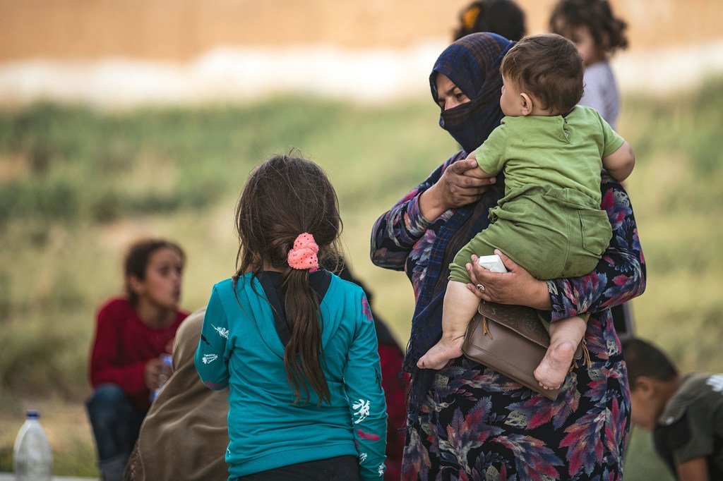 Une femme avec un enfant dans ses bras le 11 octobre 2019 en Syrie, alors que des familles déplacées arrivent à Tal Tamer, fuyant l'escalade de la violence.