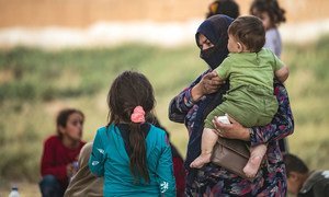 On 11 October 2019 in the Syrian Arab Republic, a woman holds a child as families displaced from Ras al-Ain arrive in Tal Tamer, having fled escalating violence.