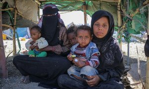在也门的一个国内流离失所者营地，一家人坐在帐篷里。