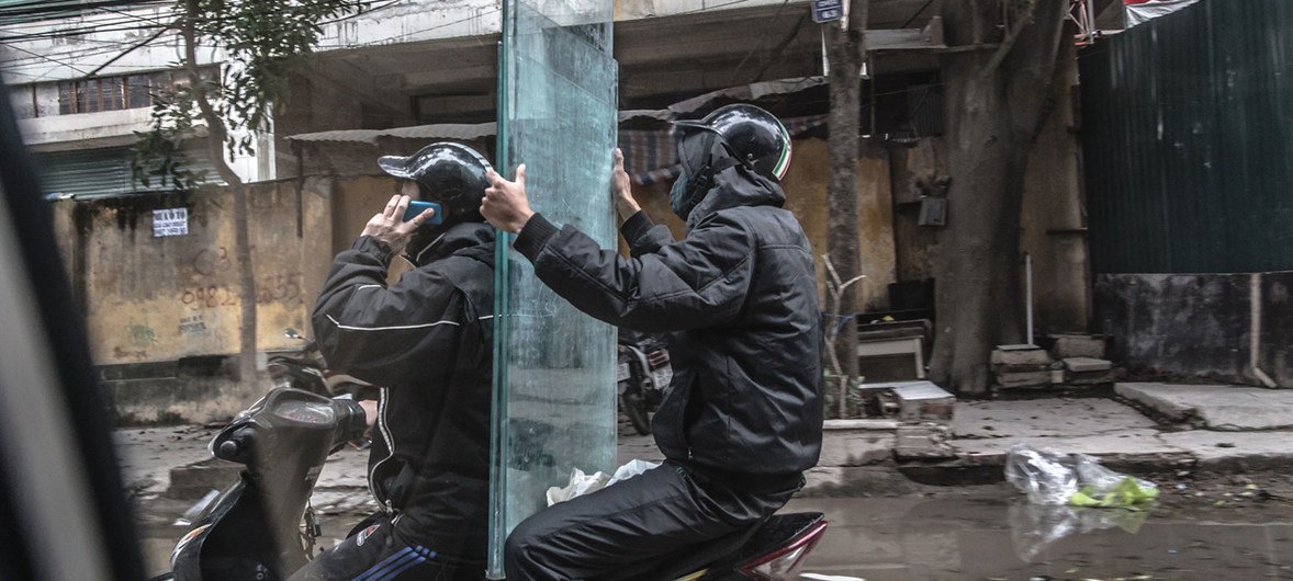Two men transport glass panels via motor scooter in Vietnam. (file)