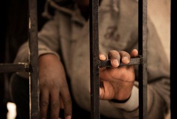 صبي مهاجر من النيجر عمره 14 عاما يضع يده على باب مركز احتجاز في ليبيا.