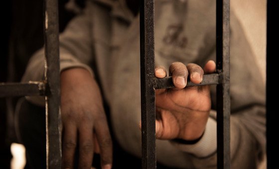 A fourteen-year-old migrant from Niger rests his hand on a gate inside a detention centre, in Libya.