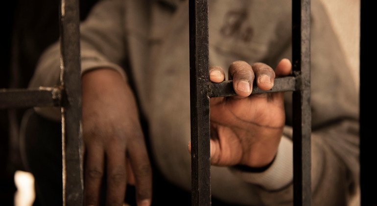 A fourteen-year-old migrant from Niger rests his hand on a gate inside a detention centre, in Libya.