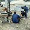 ग्रीस के लेसवॉस द्वीप स्थित मोरिया शिविर के आग में तबाह हो जाने के बाद, शरणार्थी एक अस्थाई स्थल पर खाना बकाते हुए और अपने मोबाइल चार्ज करते हुए.