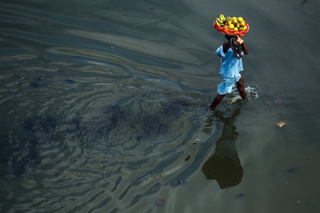 Une fille porte un panier de fruits dans une rue inondée de Cotonou, la grande ville portuaire du Bénin.