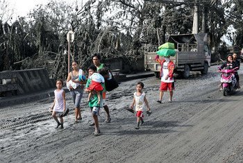 A family affected by the eruption of the Taal volcano walks in volcanic ash-covered streets.