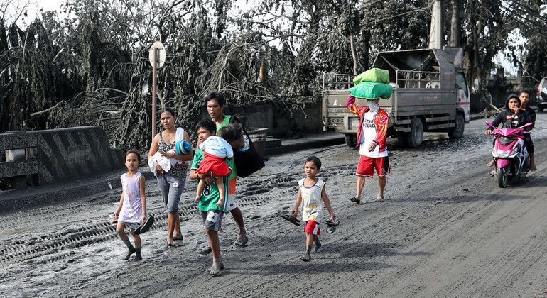 A family affected by the eruption of the Taal volcano walks in volcanic ash-covered streets.