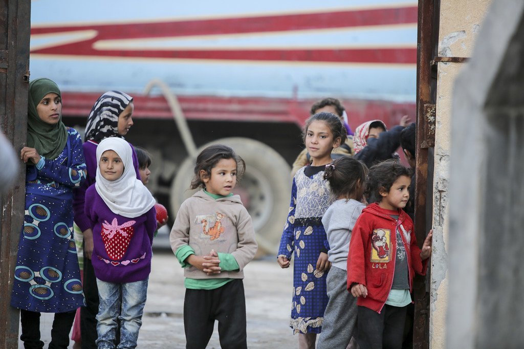 أطفال سوريون يقفون في ساحة مدرسة تحولت إلى مأوى مؤقت للاجئين في الرقة 