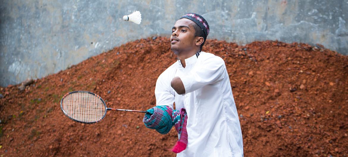 A disabled teenage boys plays badminton in front of his house in Bangladesh.