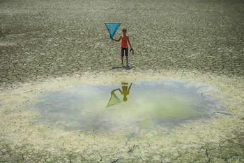 A young boy stands in front of a waterhole in a drought zone in Bangladesh.