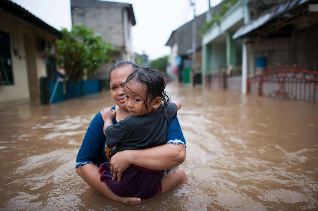 Una mujer carga a su hija tratando de ponerse a salvo durante las inundaciones en Yakarta, Indonesia.