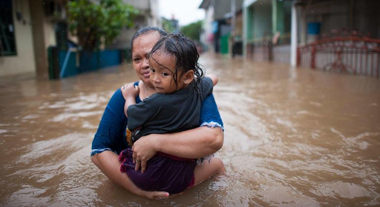 A woman carries her daughter duriing floods in Jakarta, Indonesia.