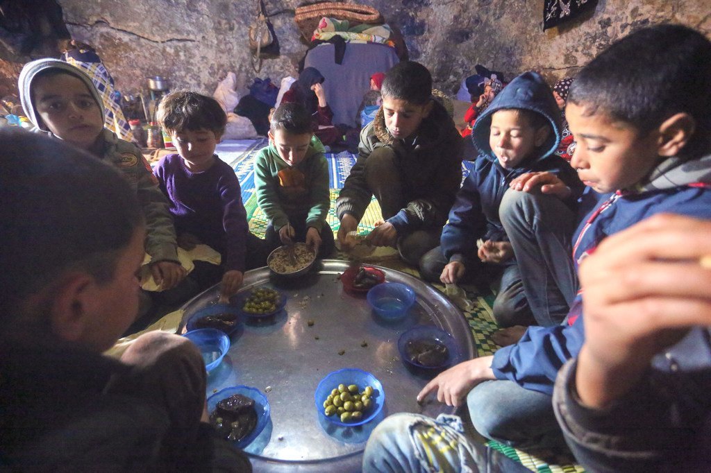 أطفال نازحون يتشاركون الطعام في كهف تحت الأرض يأوون إليه مع أسرهم في سوريا