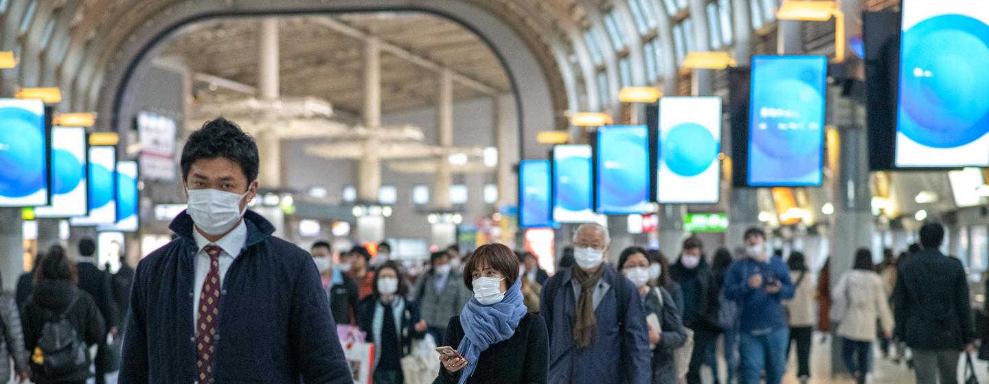 Des voyageurs portent des masques de protection à Shinagawa, à Tokyo.