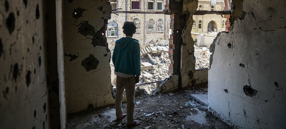 也门塔伊兹，一个男孩站在靠近活跃的前线的一栋建筑受损的内部。