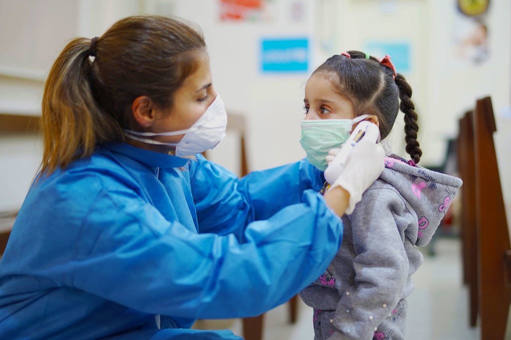 在黎巴嫩贝鲁特的一家初级卫生保健中心，一名护士在新冠疫情期间为一名女孩测量体温。