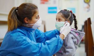 在黎巴嫩贝鲁特的一家初级卫生保健中心，一名护士在新冠疫情期间为一名女孩测量体温。
