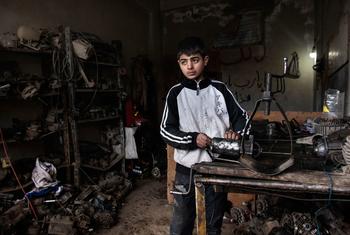 صبي يبلغ من العمر 13 عامًا يعمل في ورشة لتصليح السيارات في سوريا.