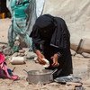 在也门，7 岁的卡里马（Karima）看着母亲哈亚特（Hayat）做面包。
