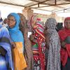 Women stand in line to receive cash distributions in Sudan.