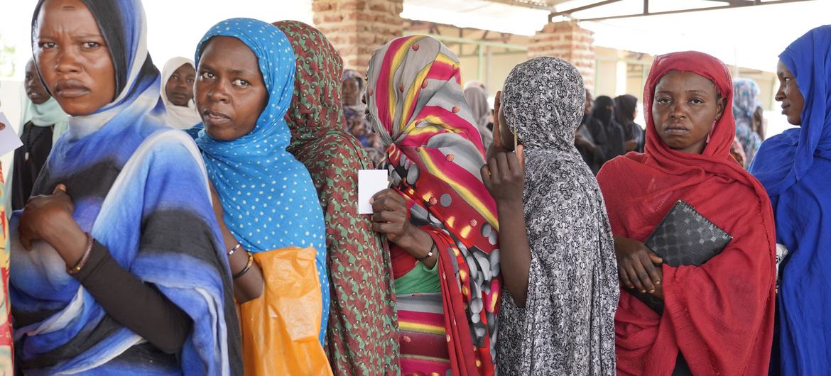 Women stand in line to receive cash distributions in Sudan.