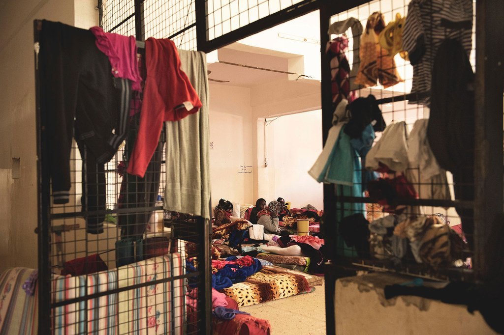 在利比亚的黎波里的拘留中心，妇女和儿童坐在地板上的床垫上。