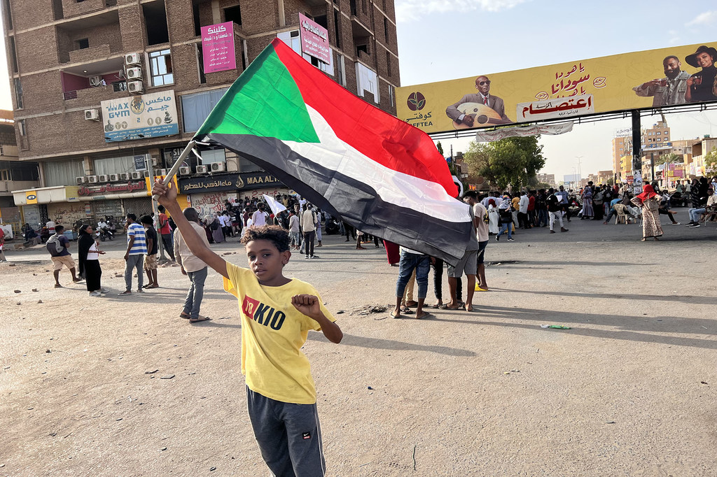 طفل متظاهر يحمل علم السودان في أحد الشوارع في الخرطوم.