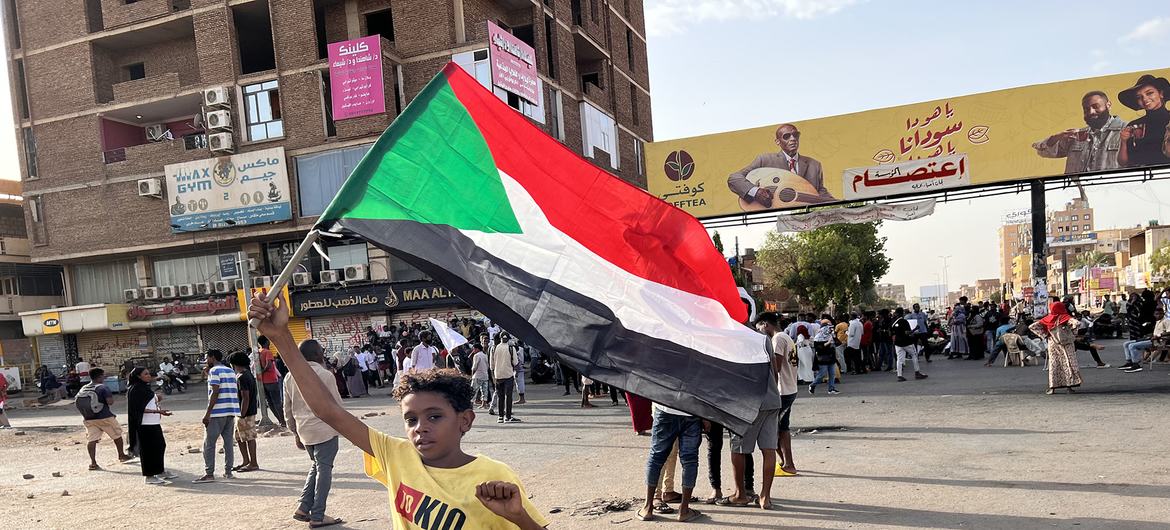 طفل متظاهر يحمل علم السودان في أحد الشوارع في الخرطوم.