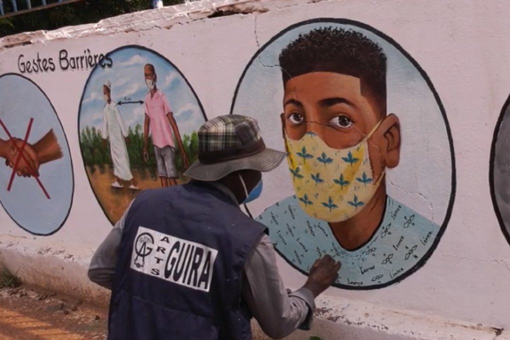 Un artiste en République centrafricaine (RCA) peignant sur les murs divers conseils pour se protéger de la Covid-19.