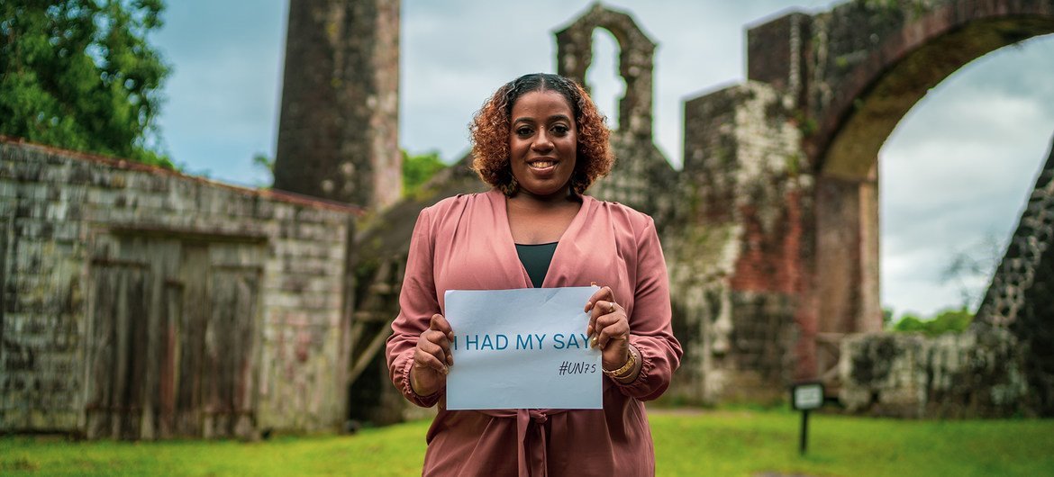 A woman from St. Kitts and Nevis in the Caribbean holds up a sign after completing the UN75 survey.